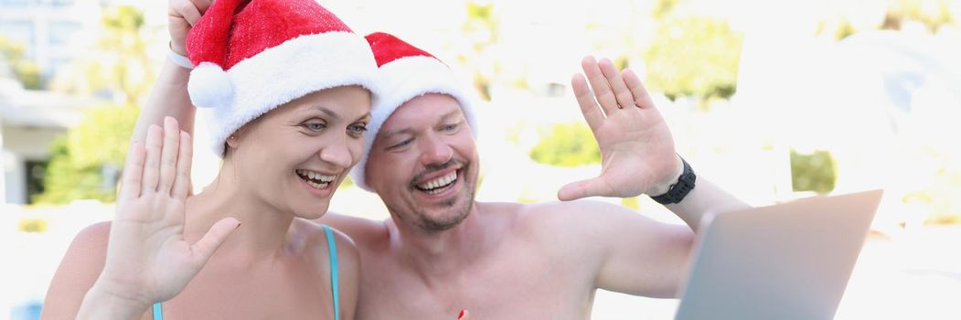 Portrait of smiling couple wave hello to family or friends on video call. Happy spouse congratulate with new year, send wishes. Holiday, summertime, christmas, new year concept