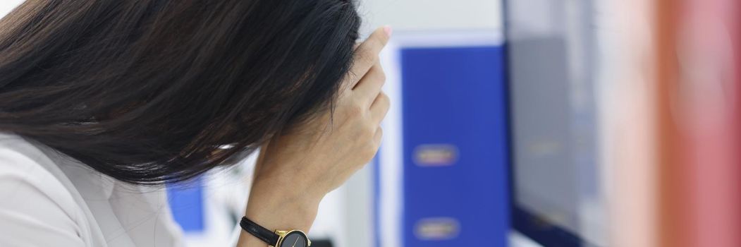 Close-up of manager sitting at table and putting head down. Overworked upset woman at workplace in office. Lot of work, routine paperwork and hard working day concept