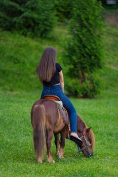 woman riding a pony on the lawn