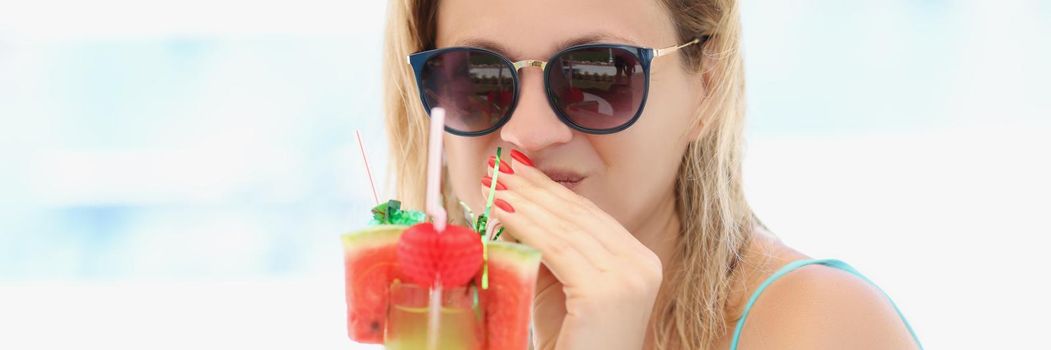 Portrait of pretty young woman enjoy taste of cocktail, chilling on private hotel territory. Girl in swimsuit and glasses sunbathe on sun. Summertime, vacation, exotic country, travel concept