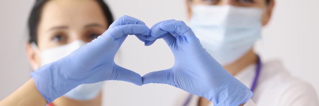 Focus on cardiologists showing heart symbol with hands in gloves. Heart disease, organ donation and healthcare idea. Cardiology, medicine and saving life concept