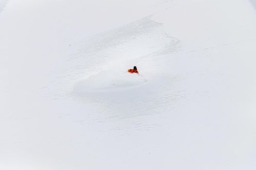 one freeride skier skiing downhill trough deep fresh powder.