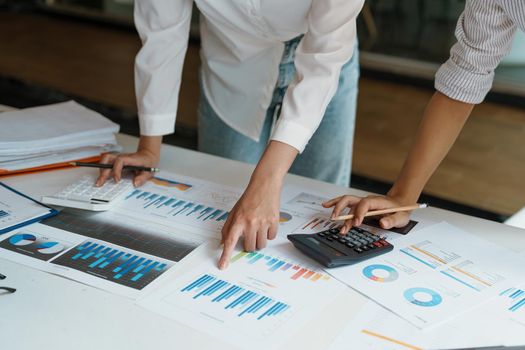 financial, Planning, Marketing and Accounting, Asian woman Economist using calculator to calculate investment documents with partners on profit taking to compete with other companies.