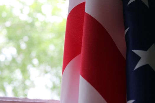 The U.S. flag hangs against a background of green foliage. Flag Day. Memorial Day. Independence Day..