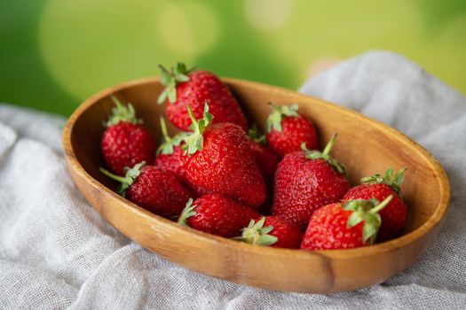 Juicy, tasty, ripe strawberries on a wooden plate, top view. Place for an inscription