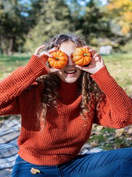 Leisure, free time. Beautiful caucasian woman in red sweater on a picnic outdoors, sitting on a plaid in autumn forest