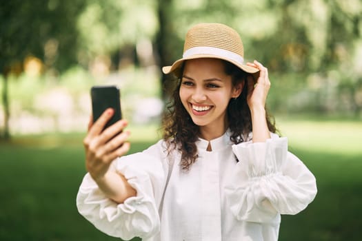 Young beautiful girl in a hat makes a selfie on her phone in the park. High quality photo