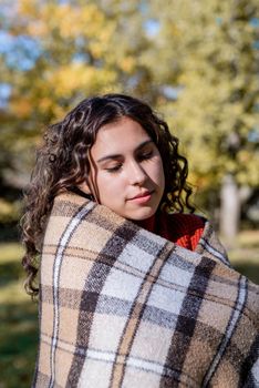 Autumn nature. Portrait of young happy woman in warm plaid in autumn forest