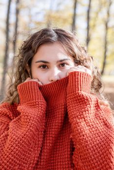 Autumn nature. Portrait of young happy woman in warm sweater in autumn forest