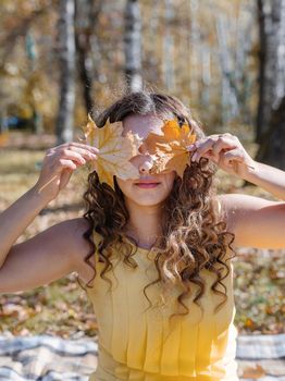 Leisure, free time. Beautiful caucasian woman in yellow dress on a picnic outdoors, sitting on a plaid in forest