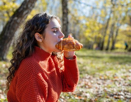 Leisure, free time. Beautiful caucasian woman in red sweater on a picnic outdoors, sitting on a plaid in autumn forest