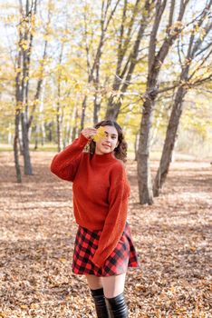 Autumn nature. young happy woman in red sweater and skirt walking in autumn forest