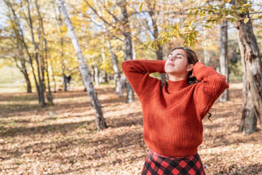 Autumn nature. young happy woman in red sweater and skirt walking in autumn forest