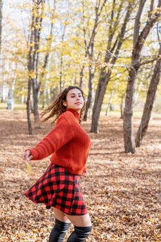 Autumn nature. young happy woman in red sweater and skirt walking in autumn forest