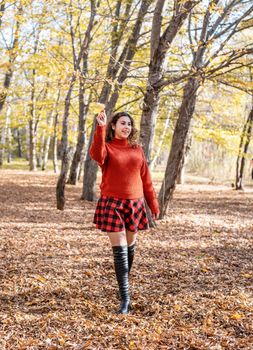 Autumn nature. young happy woman in red sweater and skirt walking in autumn forest