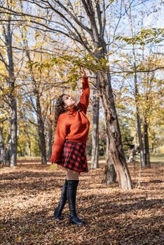 Autumn nature. young happy woman in red sweater and skirt walking in autumn forest