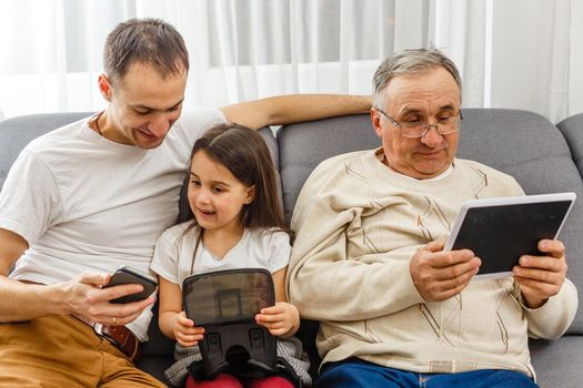 grandfather and granddaughter, father with smartphone at home.
