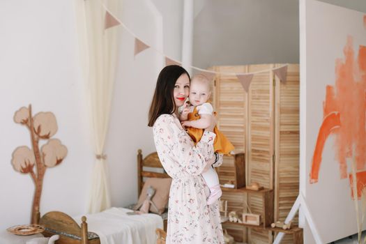 Photo of a happy mom holding and hugging little daughter, loving family sincere feelings.