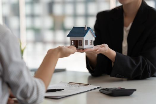 Real estate agents agree to buy a home and give house model to clients at their agency's offices. Concept agreement.