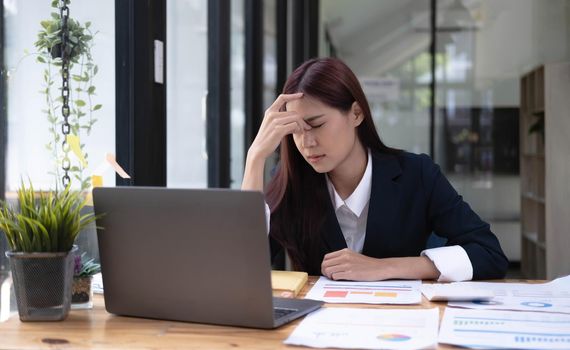 Image of an Asian business woman is stressed, bored, and overthinking from working on a tablet at the office..