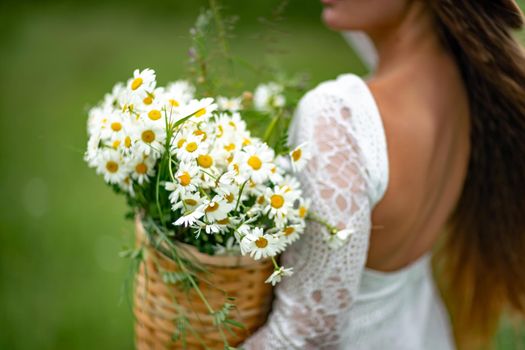 A middle-aged woman holds a large bouquet of daisies in her hands. Wildflowers for congratulations.