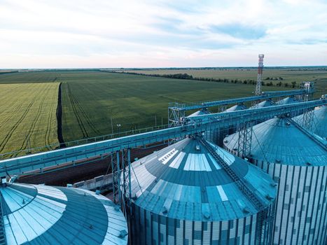 Grain elevator. Metal grain elevator in agricultural zone. Agriculture storage for harvest. Grain silos on green nature background. Exterior of agricultural factory