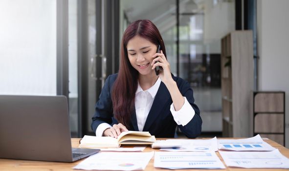 Asian business woman have the joy of talking on the phone, laptop and tablet on the office desk..