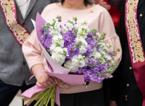 Bouquet at school teacher and students with a graduation ribbon 2022