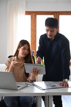 Beautiful businesswoman showing information on digital tablet to her male colleague.