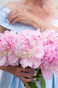 bride in a blue wedding dress with a bouquet of pink peonies, pastel paradise, floral background, complementary color combination. High quality photo
