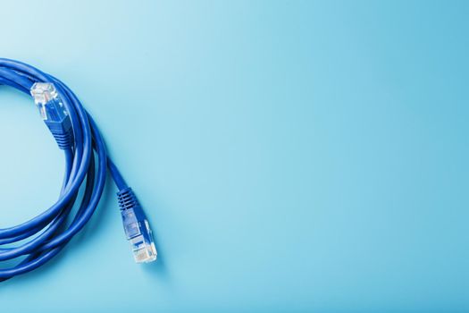 Blue Ethernet Cable Connectors Patch cord cord close-up isolated on a blue background with free space