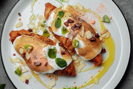 croissant with sweet cream and almonds on a plate. Delicious and healthy breakfast.