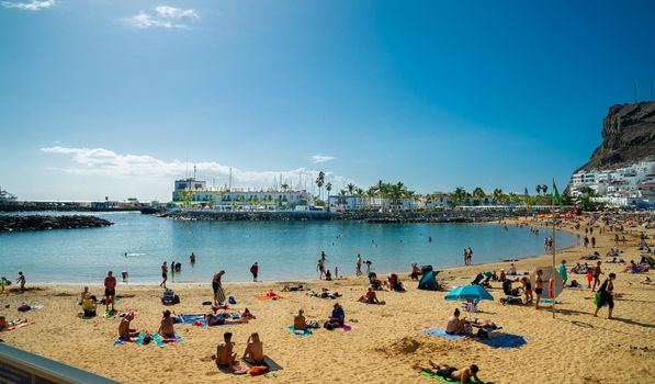 February 02 2022 Playa de Mogan in gran canaria a very beautiful place visited by many tourists who sit at the beach on the yellow sand and in the background you can see the Atlantic Ocean