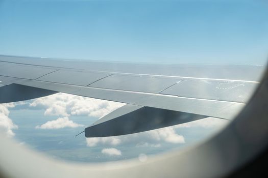 View of the wing of an airplane and the sky with clouds from the airplane window. Selective focus.