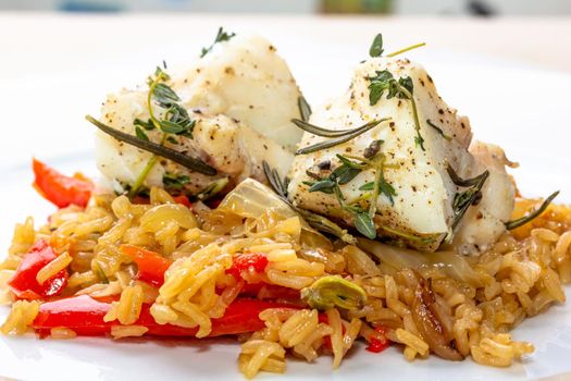 Fish dish - fried cod fillet with boiled white rice and fresh fruit salsa on white table.