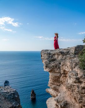 A woman in a red flying dress fluttering in the wind, against the backdrop of the sea