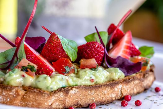 Keto diet avocado toast with strawberries, soft cheese, sesame seeds and herbs. healthy Breakfast or lunch. sandwich recipe mix media. top view, selective focus .