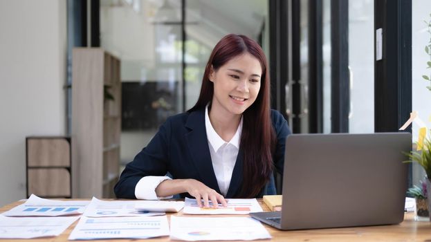 Close up portrait of a beautiful young Asia woman smiling and looking at laptop screen.