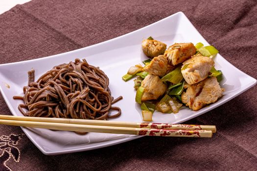 Japanese buckwheat noodles Yakisoba with chicken and vegetables on a light background.