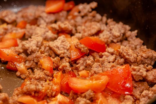 Bolognese ragout in a frying pan with wooden spoon, authentic recipe, close-up.