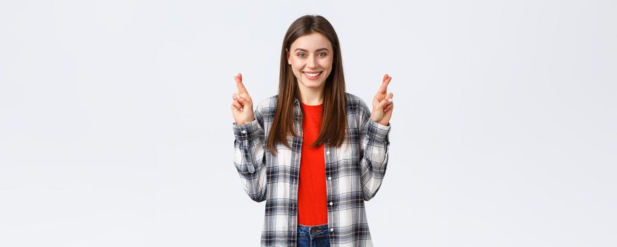 Lifestyle, different emotions, leisure activities concept. Hopeful cute caucasian girl in checked shirt, making wish, cross fingers good luck and smiling optimistic, white background.