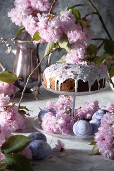 beautiful Easter cake on the table, and colored eggs, homemade cakes, still life with a silver teapot on a background of pink sakura. High quality photo