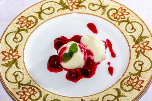 Panakota with cherry jelly and mint leaves on a white background.