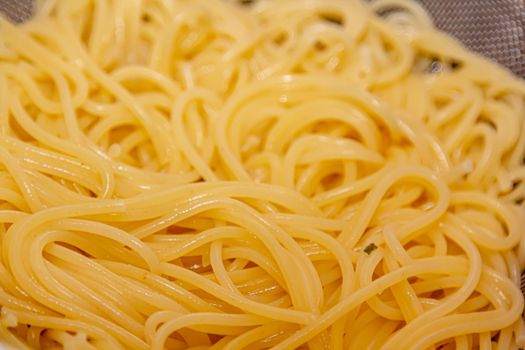Closeup view of fresh boiled spaghetti pasta inside colander. Shallow depth of field.