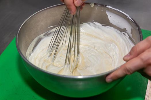 whisking egg yolks and sugar in a bowl.