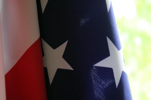 The U.S. flag hangs against a background of green foliage. Flag Day. Independence Day. Memorial Day..
