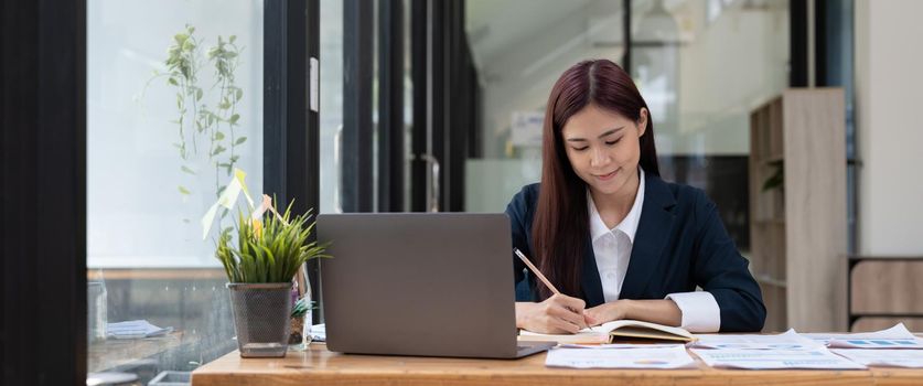 Business accountant asian woman using calculator for do math finance on wooden desk in office and business working background, tax, accounting, statistics and analytic research concept.