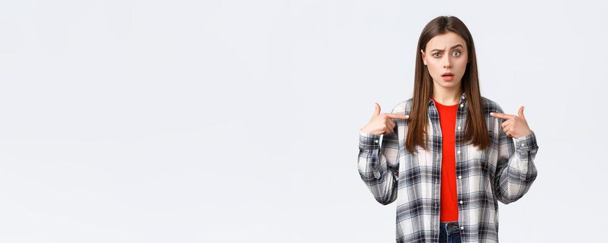 Lifestyle, different emotions, leisure activities concept. Confused young girl cant understand why she. Puzzled woman pointing at herself with raised eyebrow, being chosen, white background.