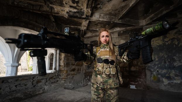 Caucasian woman in army uniform holding two machine guns