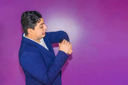 Nicaraguan man in blue formal suit looking at his smart watch on plain purple background